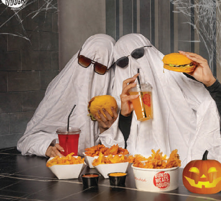 Halloween shoot: two people in ghost sheets and sunglasses with burgers, fries and a jack-o-lantern