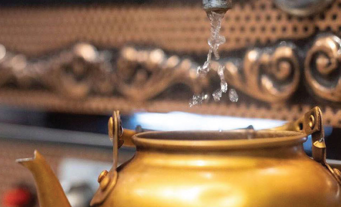Brass teapot pouring water, close-up