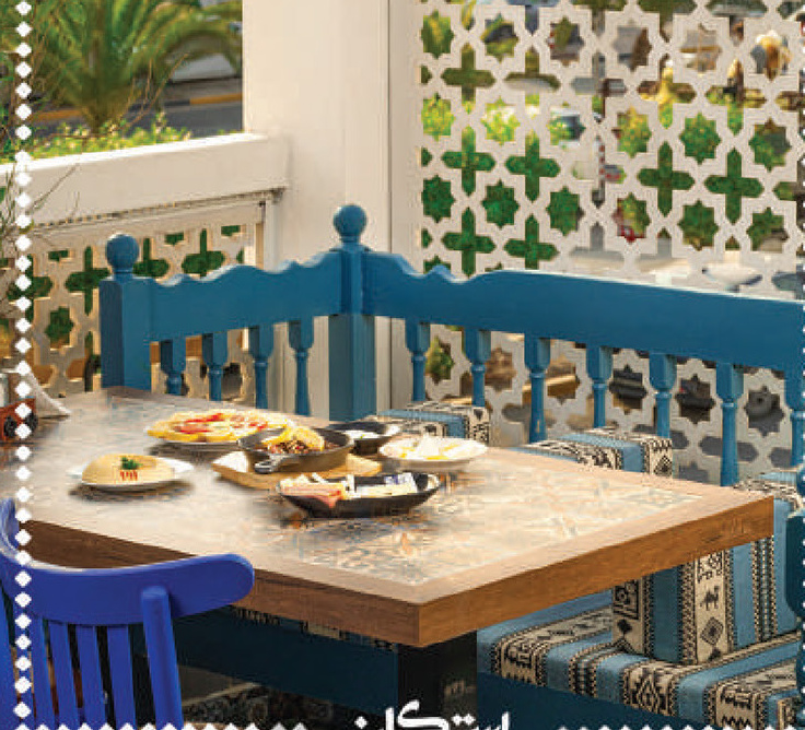 Blue wooden bench and table with mezze in front of a mashrabiya screen