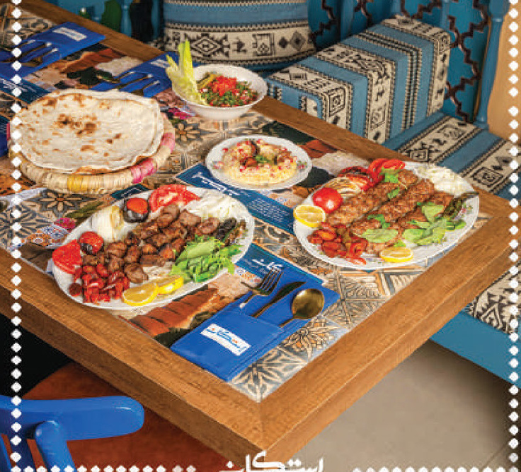 Grilled kebab platters with bread and salads on a tiled table
