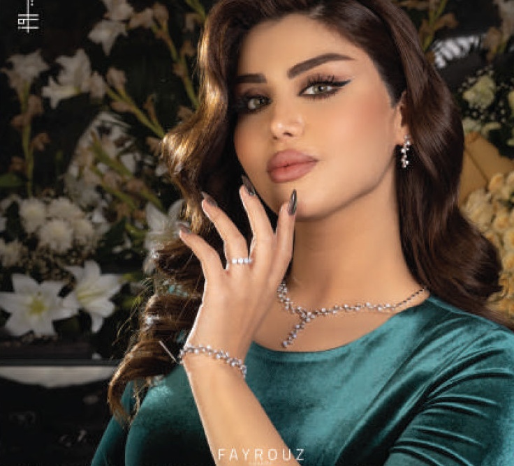 Model wearing a necklace, bracelet and ring against white lilies