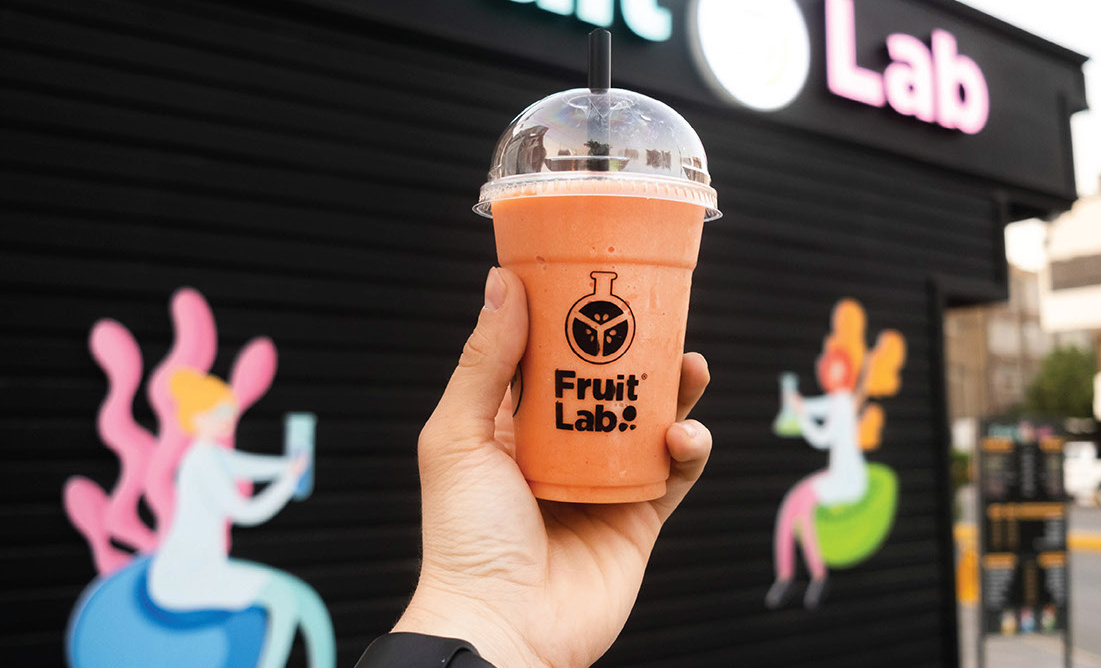 Orange smoothie cup held up in front of the illustrated kiosk