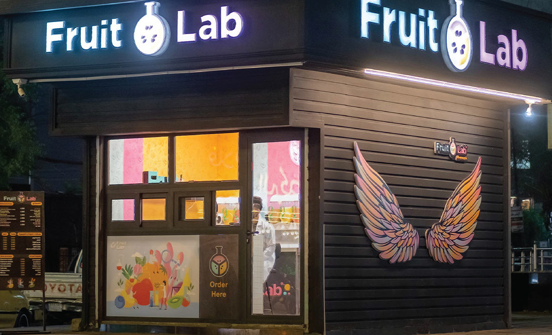 Fruit Lab kiosk at night with the wings mural